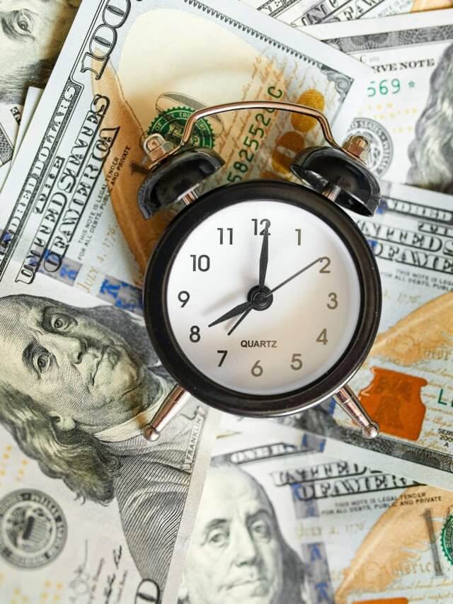 Top view flat lay of Alarm clock and money on white wooden background
